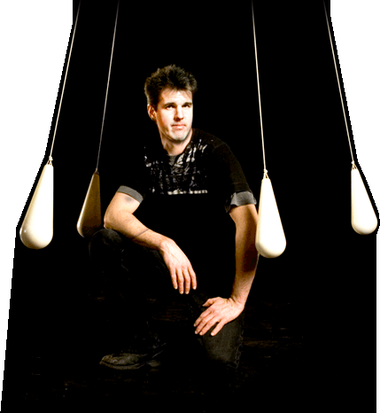 Pendulum: Greg Kennedy kneeling between four rotating pendulums suspended from above